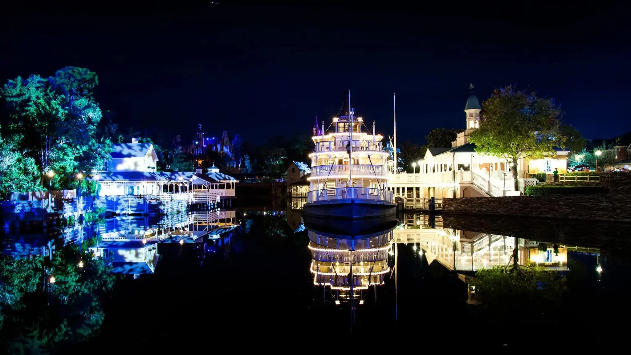 A Disney ferry shining bright on the water at night.