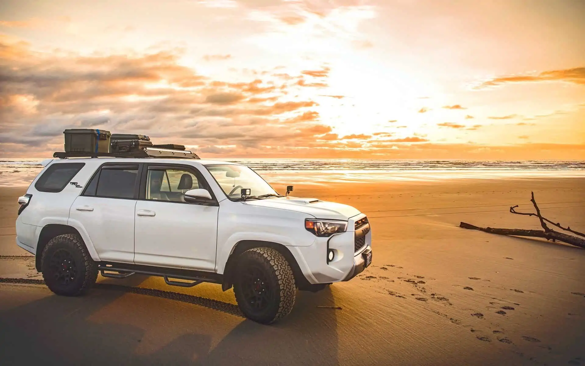 Gorgeous sunset behind car on beach.